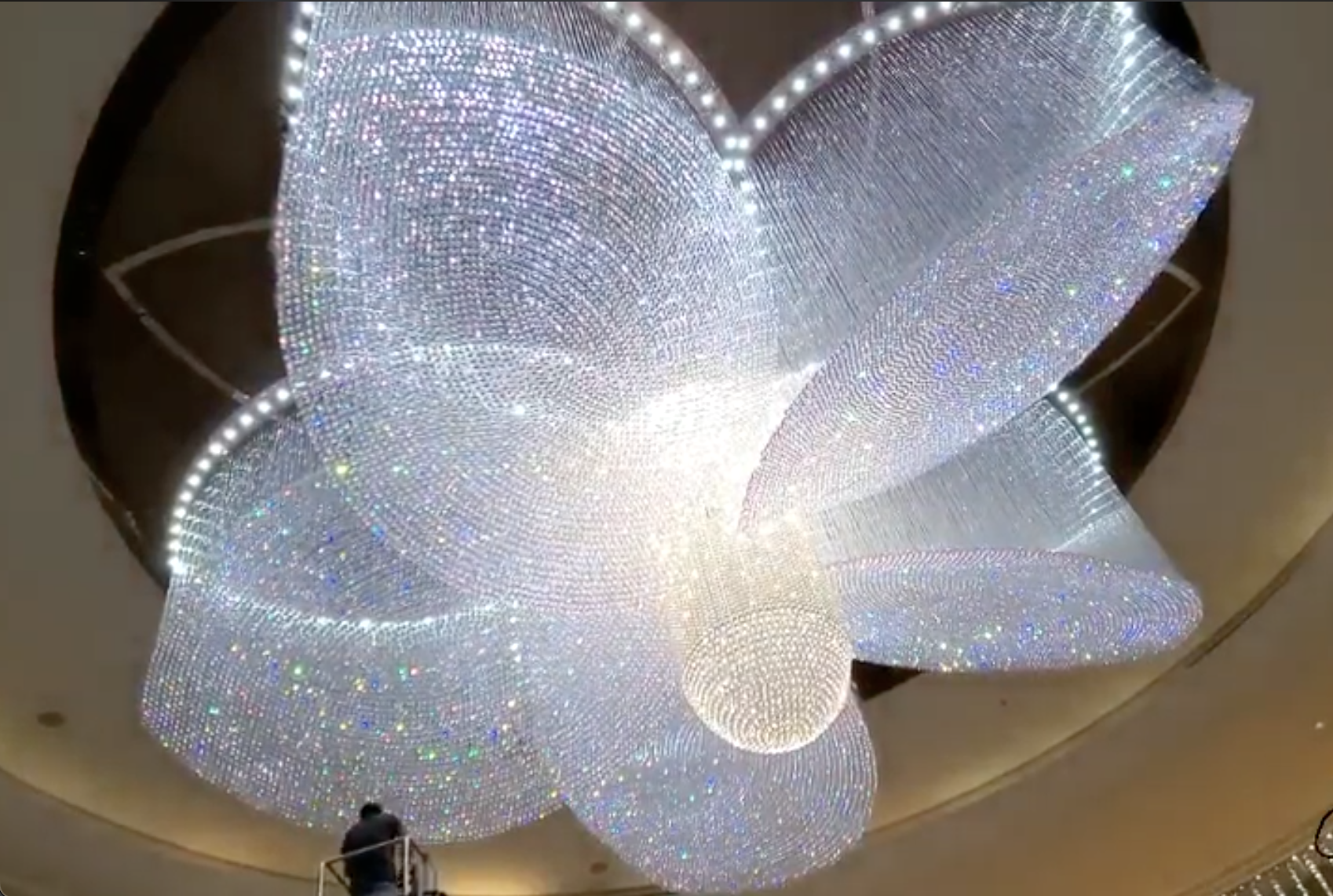 Large-scale fibre optic crystal chandelier with person on ladder for scale