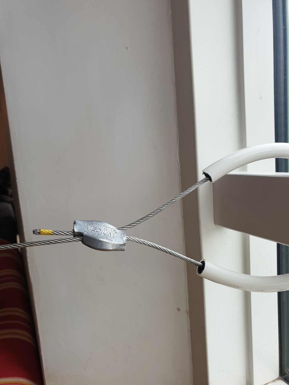 Gripple Plus Medium connector joining a 3mm cable loop around a beam, with white hose protecting the beam surface